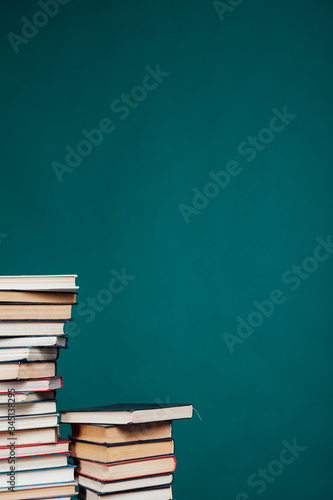 many stacks of educational books for exams at the university in the library on a green background