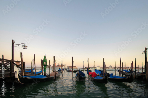 Fototapeta Naklejka Na Ścianę i Meble -  Several gondolas moored nearby Saint Mark square, early morning, tranquil sunrise atmosphere, usually serving tourists for transportation around the narrow canals, in Venice, Italy