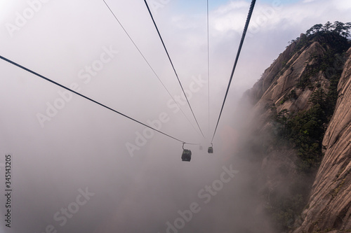 Teleférico subiendo montaña con niebla