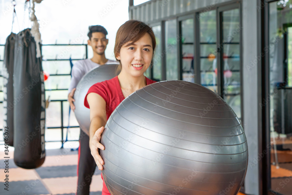 Healthy young woman and the man working out with exercise ball in the gym. Sport, fitness, lifestyle and Helthy concept