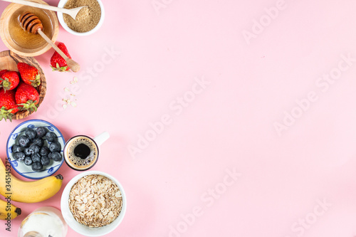 cereal and various delicious ingredients for breakfast on a pink background, top view copy space frame