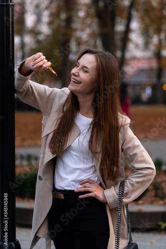 Obraz na płótnie Outdoor fashion portrait of stylish young woman having fun, emotional face , laughing, Urban city street style wearing dark casual trousers, white sweater,creamy coat. and sunglasses Fashion concept. w salonie