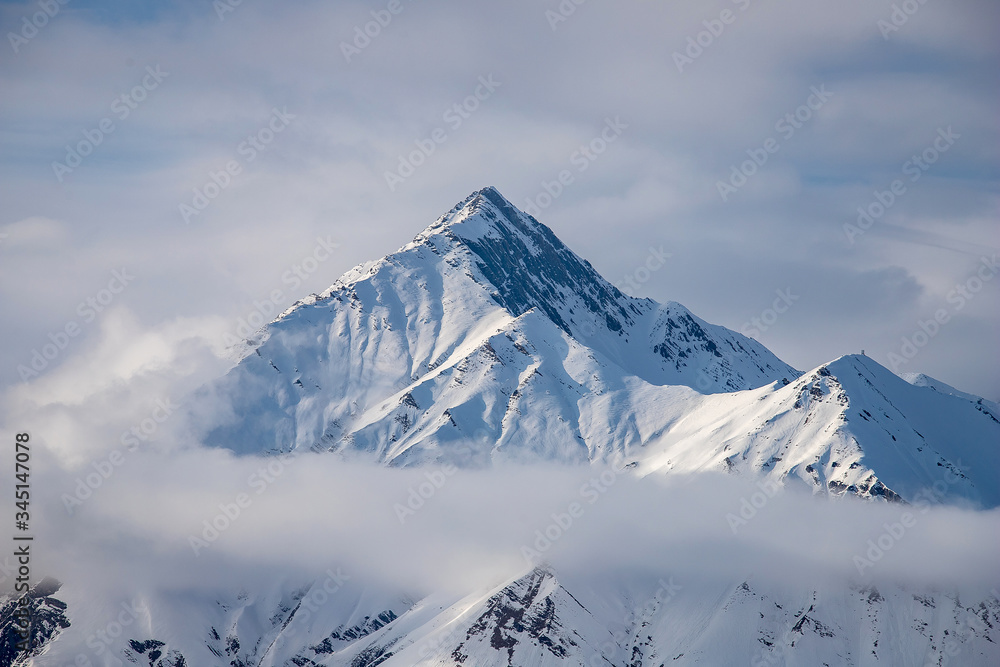 Beautiful snowy mountain peak of the Caucasus mountains in the clouds