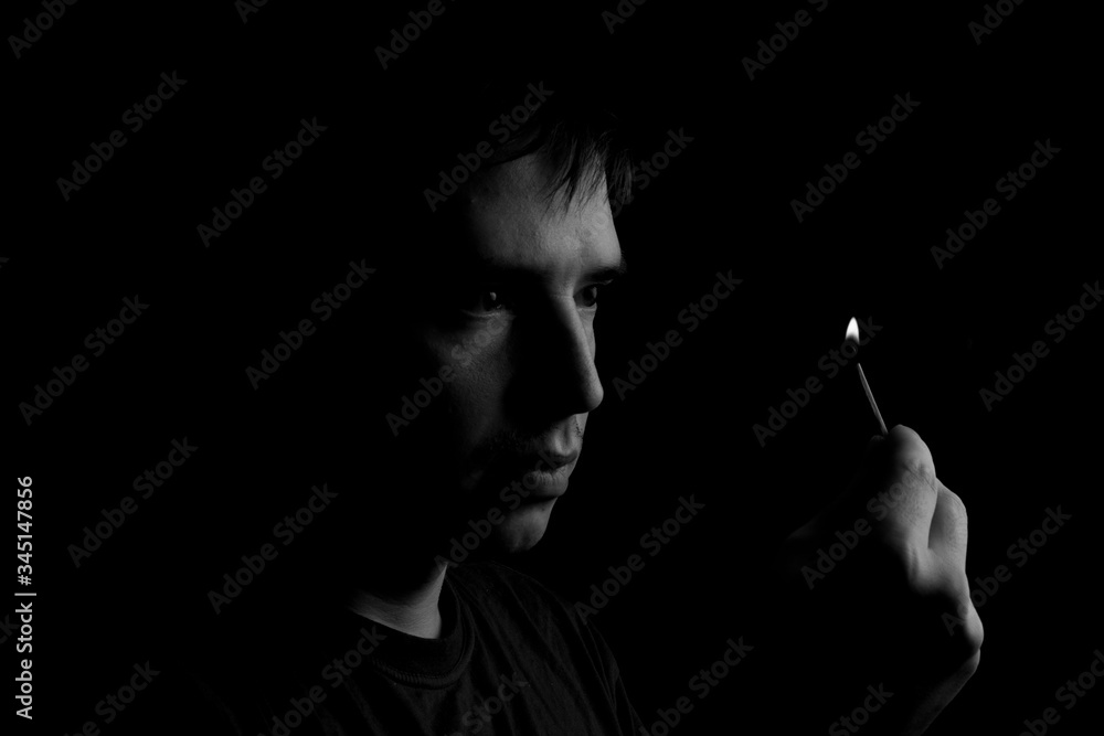 Fototapeta premium man holds a burning match. Fire from matches on a dark background. Photo with copy space.