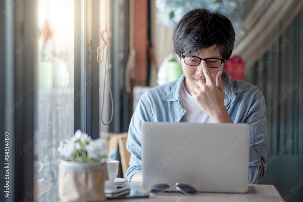 Asian freelance man adjust glasses using laptop computer in the cafe. Businessman in casual clothing doing online conference or telecommuting. Remote work from anywhere. Smart working with technology Asian freelance man adjust glasses using laptop computer in the cafe. Businessman in casual clothing doing online conference or telecommuting. Remote work from anywhere. Smart working with technology