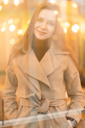 Outdoor fashion portrait of stylish young woman having fun, emotional face , laughing, Urban city street style wearing dark casual trousers, white sweater,creamy coat. and sunglasses Fashion concept.