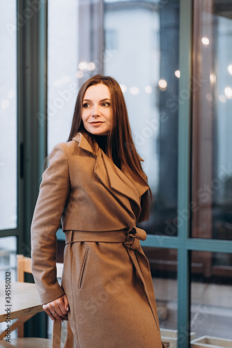 Obraz na płótnie Outdoor fashion portrait of stylish young woman having fun, emotional face , laughing, Urban city street style wearing dark casual trousers, white sweater,creamy coat. and sunglasses Fashion concept. w salonie