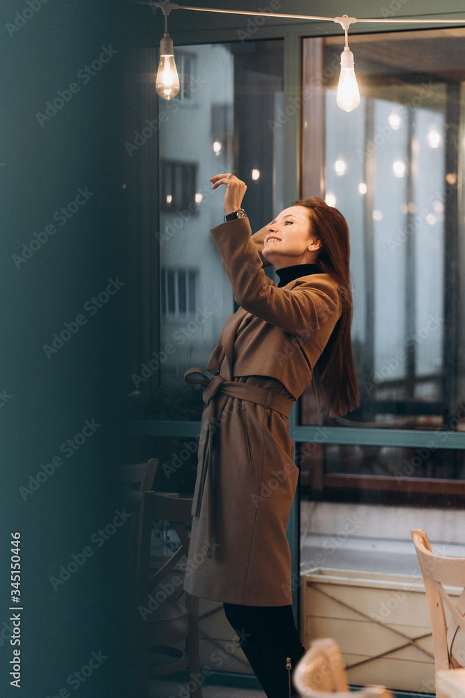 Outdoor fashion portrait of stylish young woman having fun, emotional face , laughing, Urban city street style wearing dark casual trousers, white sweater,creamy coat. and sunglasses Fashion concept.