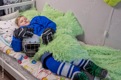 Young hockey player sleeping in his bed in full hockey outfit between training sessions. The era of the coronavirus epidemic and its consequences. Self-isolation and distance learning skill.