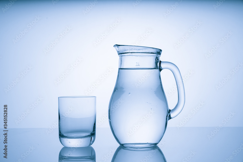 Pitcher with drinking water and a glass with a drink, blue tone Pitcher with drinking water and a glass with a drink, blue tone