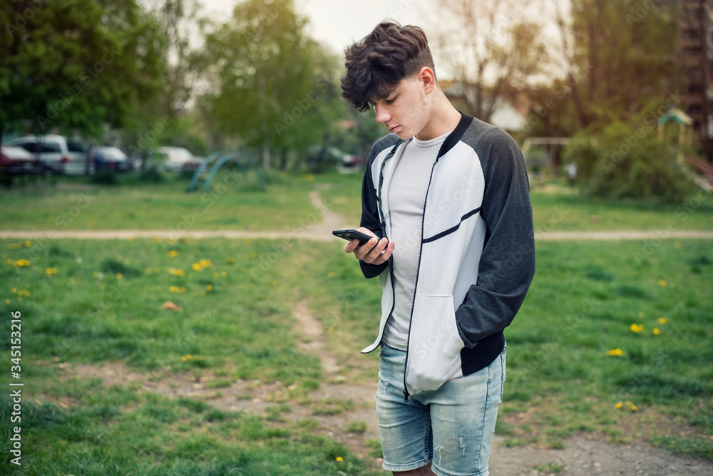 A teenage boy holds a modern phone in his hands and starts to call his parents to say that everything is fine with him, because he went to a friend in another city A teenage boy holds a modern phone in his hands and starts to call his parents to say that everything is fine with him, because he went to a friend in another city