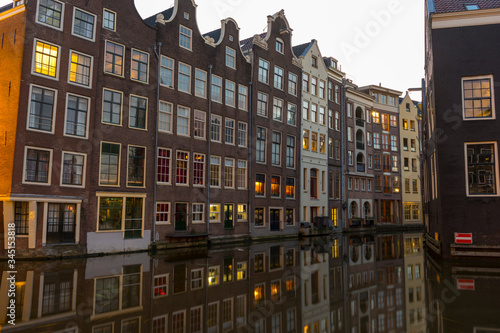 Famous dancing houses and buildings in Amsterdam with reflection in canal water. © bennnn