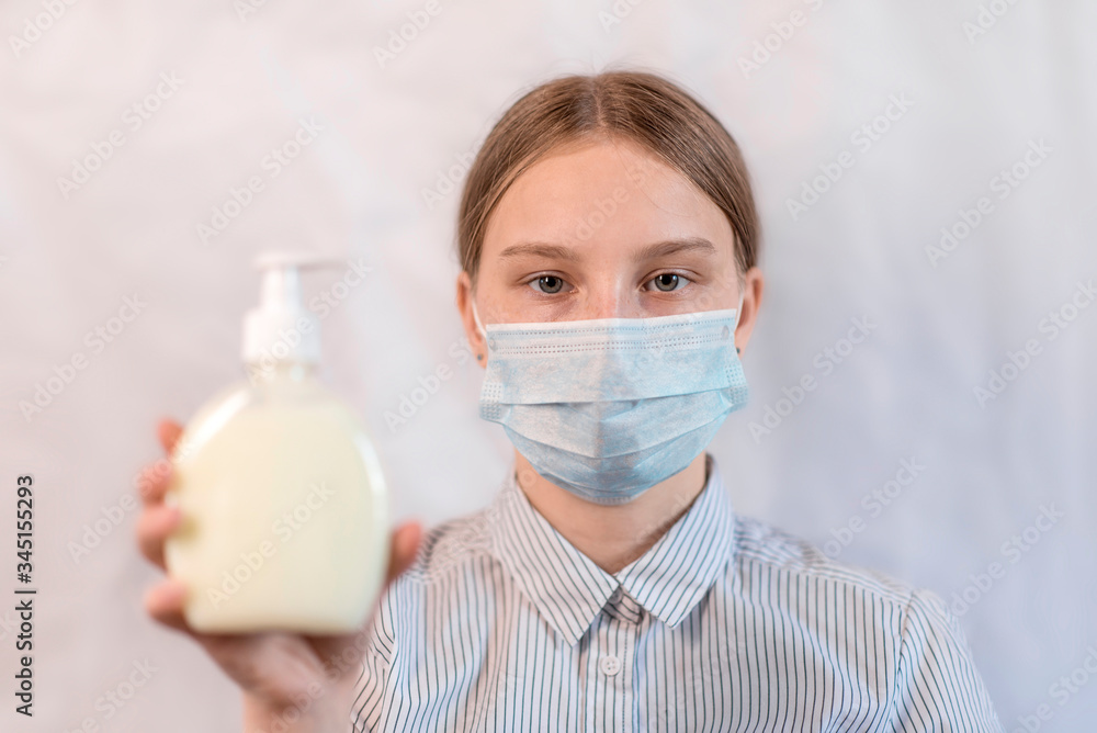 Teen girl protective mask holding antiseptic liquid soap in hand on white background, anti-coronavirus COVID-19 pandemic infectious disease outbreak protection, healthcare concept
