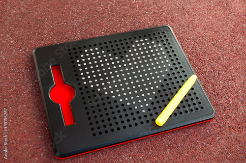 Close-up of a mosaic for children with the image of a heart on a red background. Metal heart on a children's black magnetic puzzle. The concept of children's and teenage love. Children toy. 