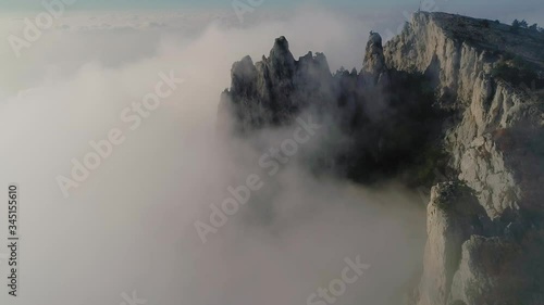 The canyon of the Crimea is a popular place, fog, rocks in the clouds, teeth of stone, drone flight over the clouds, smooth flight at the height of a bird's flight, the black sea