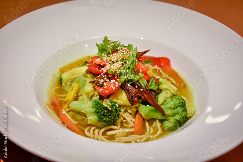 delicious asian noodle soup with vegetables on white plate