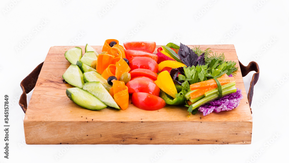 Dishes of fresh vegetables on a wooden board on a white background
