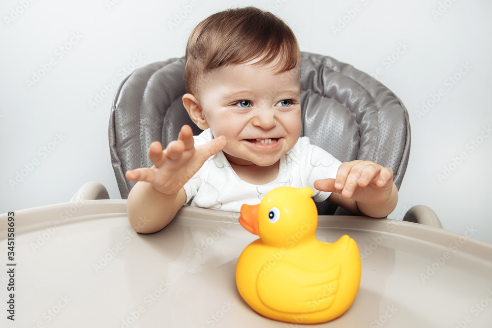 Happy excited adorable baby boy play with duck toy in high chair. Happy excited adorable baby boy play with duck toy in high chair.