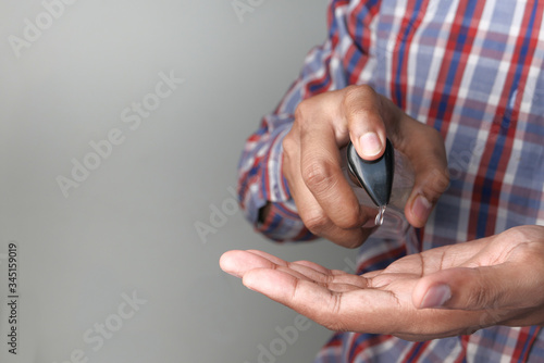 young man with casual dress using hand sanitizer for preventing virus 