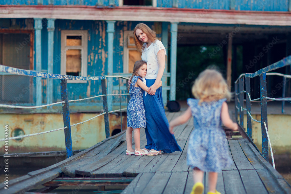 Obraz premium mom and kids in blue clothes standing old bridge