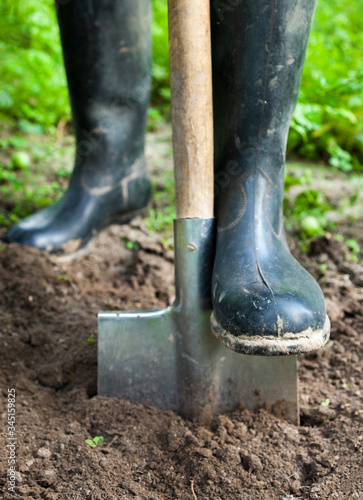 Foot in rubber boot on the metal spade