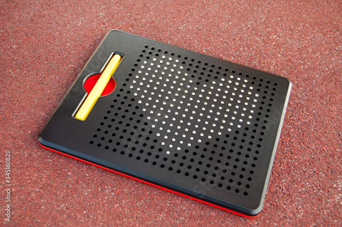 Close-up of a mosaic for children with the image of a heart on a red background. Metal heart on a children's black magnetic puzzle. The concept of children's and teenage love. Children toy. 