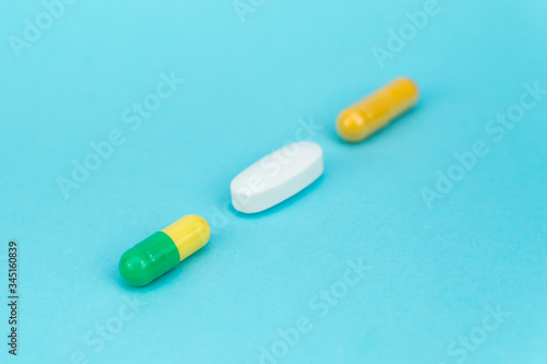 three multi-colored pills lie diagonally on a blue background