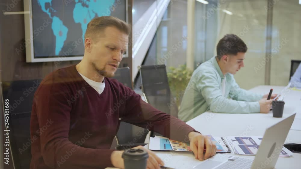 Tracking shot of group of business people working with data separately sitting at desk in office behind glass wall. Exhausted middle aged man rubbing tired eyes and looking away pensively Tracking shot of group of business people working with data separately sitting at desk in office behind glass wall. Exhausted middle aged man rubbing tired eyes and looking away pensively