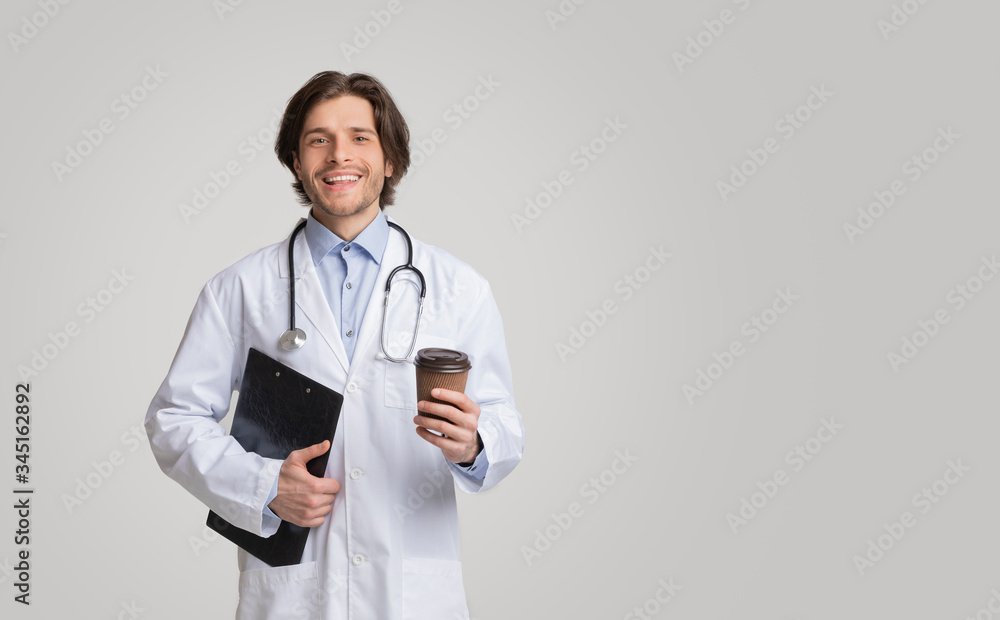 Portrait of young smiling doctor holding medical chart and takeout coffee Portrait of young smiling doctor holding medical chart and takeout coffee