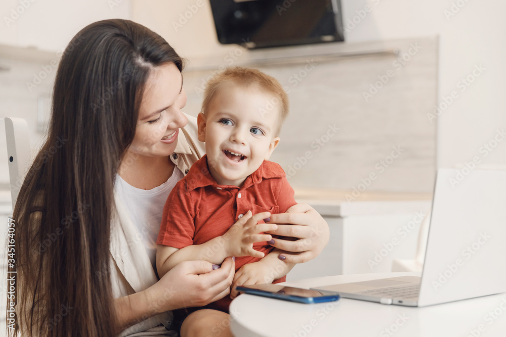 Business mom is using online work laptop, woman spending time with her boy baby home Business mom is using online work laptop, woman spending time with her boy baby home