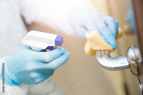 Disinfection and cleaning door handles of house from infection with virus and microbes in biochemical suit. Coronavirus protection concept