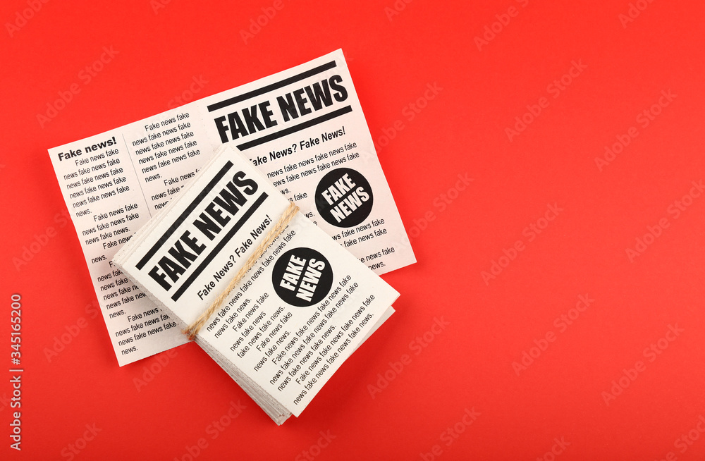 Stack of FAKE NEWS newspapers over red Stack of FAKE NEWS newspapers over red