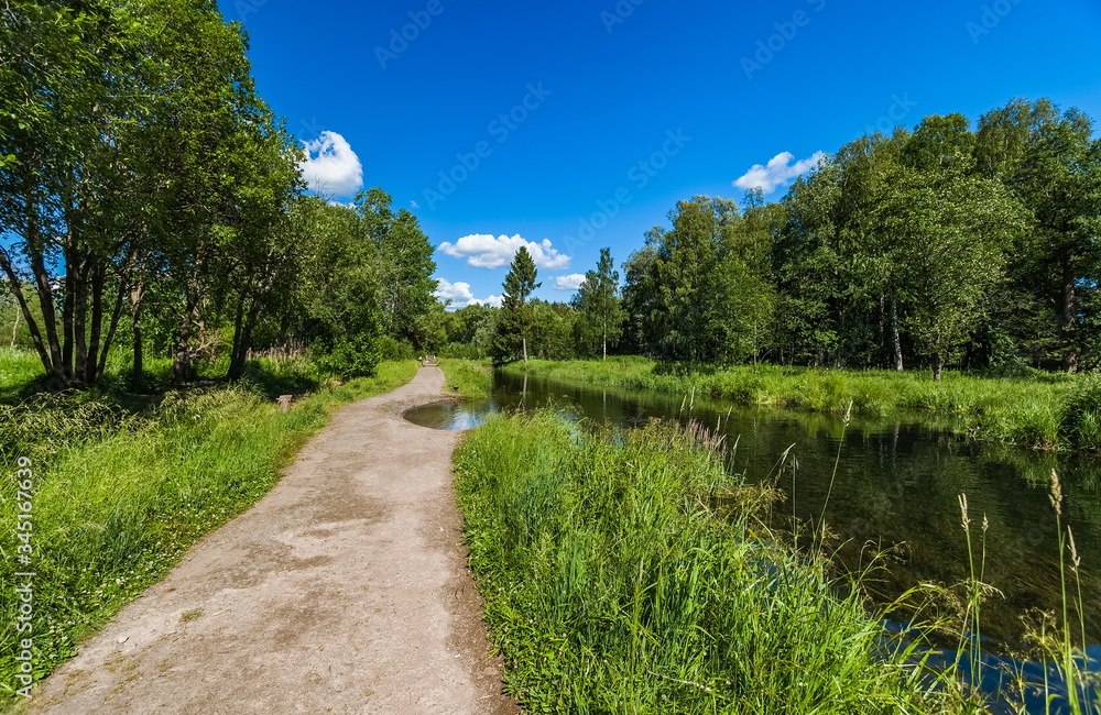 Summer landscape with a river, a path along the river, trees, grass and a blue sky with white clouds Summer landscape with a river, a path along the river, trees, grass and a blue sky with white clouds