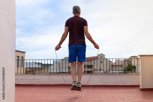 Man working out with a skipping rope on the terrace of his house