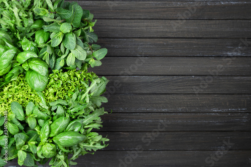 Fresh fragrant green variety of herbs on a dark brown wooden background. basil, cilantro, peppermint, spinach, salad, arugula. copy space, flat lay
