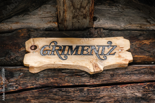 Wooden artisan nameplate of Grimentz hanging on aged wood boards in a chalet or log cabin. Grimentz, Val d' Anniviers, Valais, Switzerland
