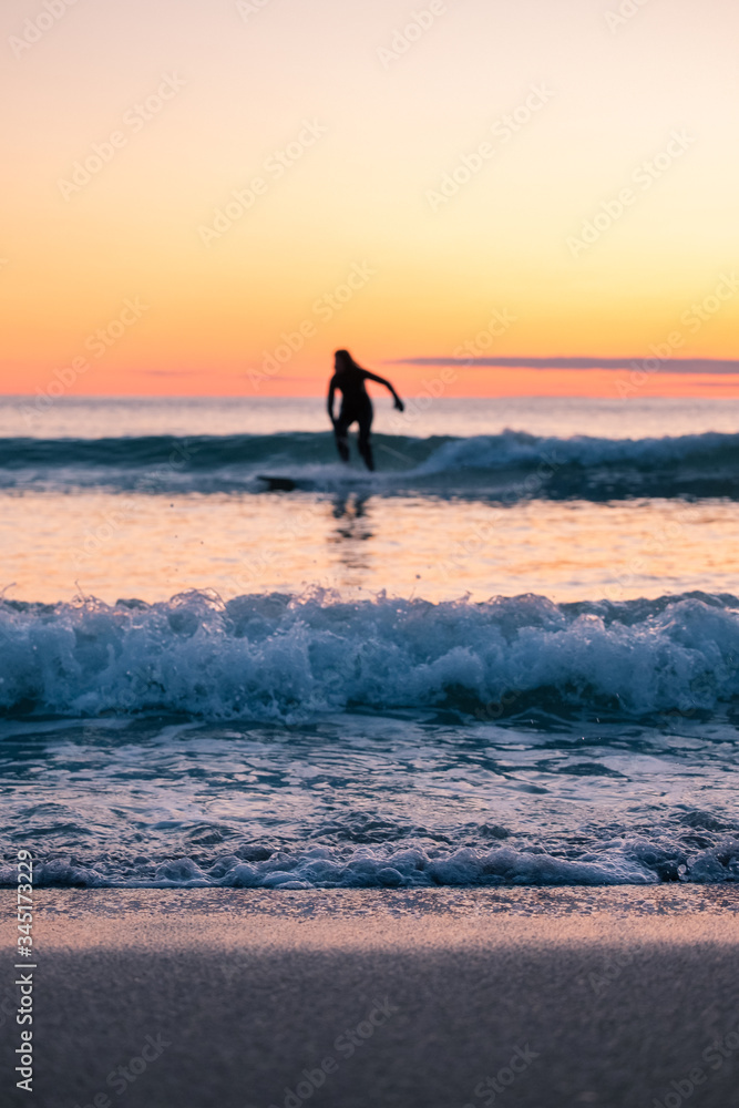 Blurred surfer on longboard. small waves during beautiful sunset. surfing behind arctic circle has advantage of midnight sun. Unstad is a famous beach in Lofoten Islands