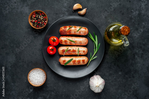 classic grilled sausages with spices in a plate on a stone background