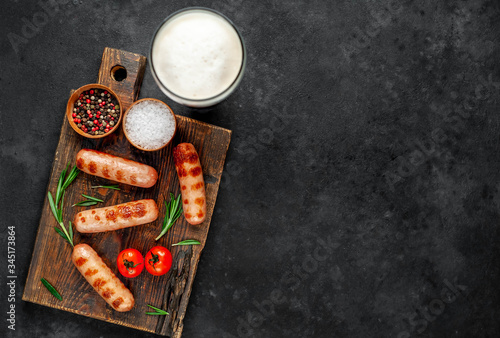 Beer and classic grilled sausages with spices on a stone background with copy space for your text