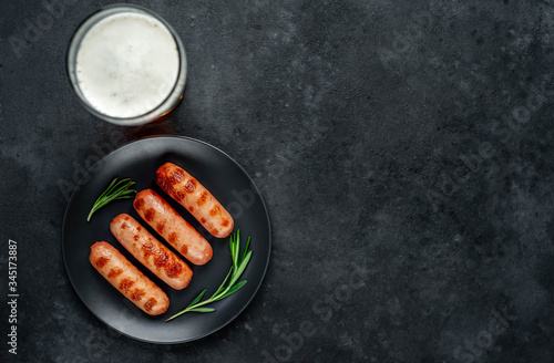 Beer and classic grilled sausages with spices on a stone background with copy space for your text