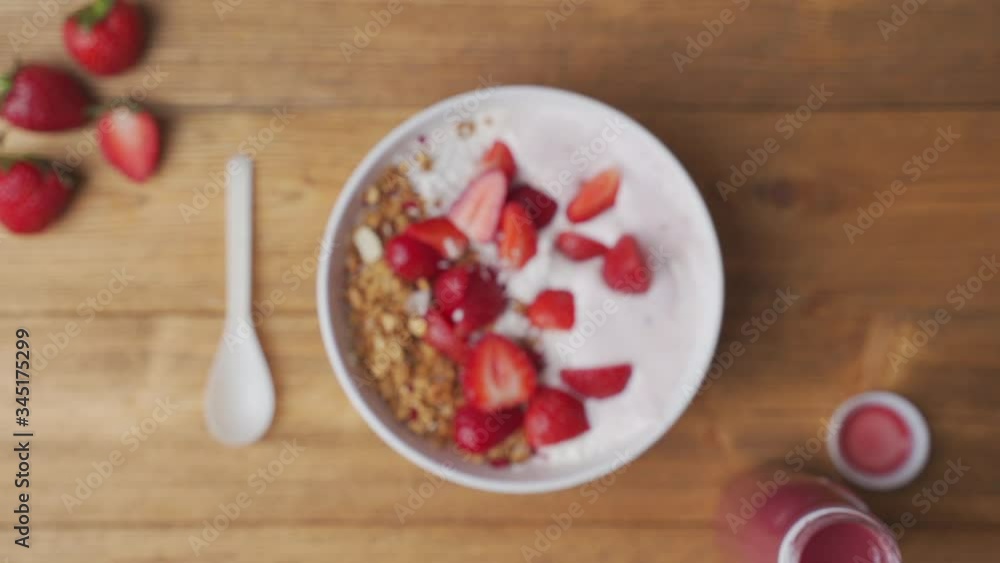 Strawberries falling in a bowl of yogurt with granola Strawberries falling in a bowl of yogurt with granola