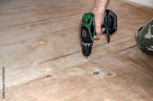 Carpenter screw screwdriver spin into a sheet of plywood. Repair floor.