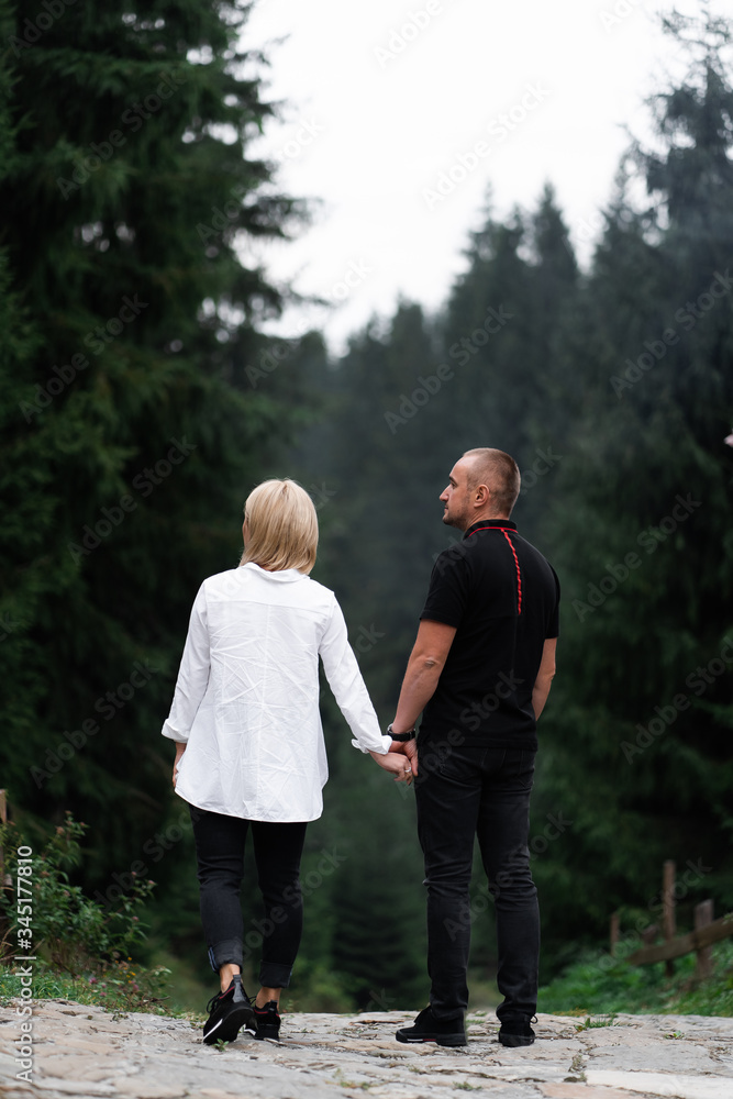 A man next to a woman, guy and a girl are standing close, touching each other, holding hand on forest background. Boy and girl, couple. Intimacy, honesty, trust. Bright future. Couple