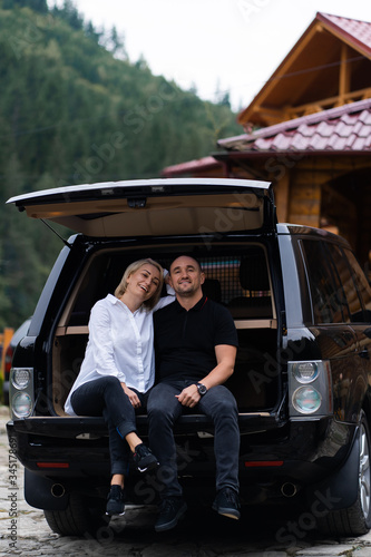 Portrait of beautiful sexy blonde woman and man sitting in luxury dark car . Fashion and business concept. Idea for couple photoshoot with car. Valentines day, surprise. © MONIUK ANDRII