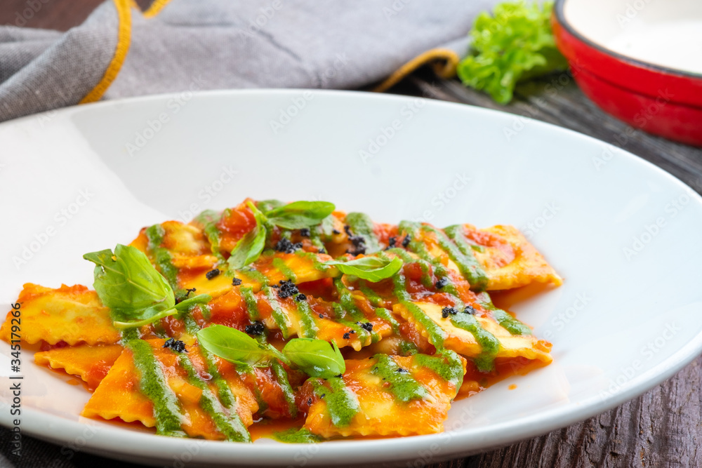 Classic ravioli with tomato sauce and Basil leaves on a white plate, close up Classic ravioli with tomato sauce and Basil leaves on a white plate, close up