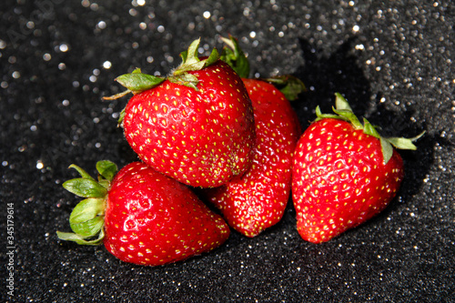 4 strawberries on a black background. Berries on a dark shiny background.