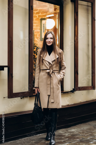Obraz na płótnie Outdoor fashion portrait of stylish young woman having fun, emotional face , laughing, Urban city street style wearing dark casual trousers, white sweater,creamy coat. and sunglasses Fashion concept. w salonie