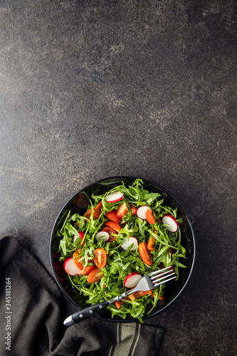 Fresh arugula salad with radishes, tomatoes and red peppers.