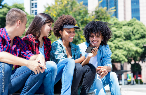 Happy hispanic and african american hipster young adult people with phone photo