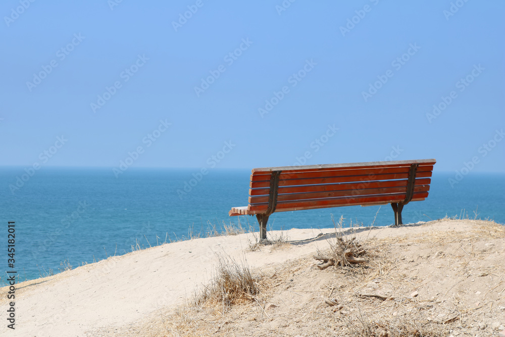 Fototapeta premium Lonely red painted bench with nice view on the Mediterranean Sea, Ashkelon, Israel. Low key filter